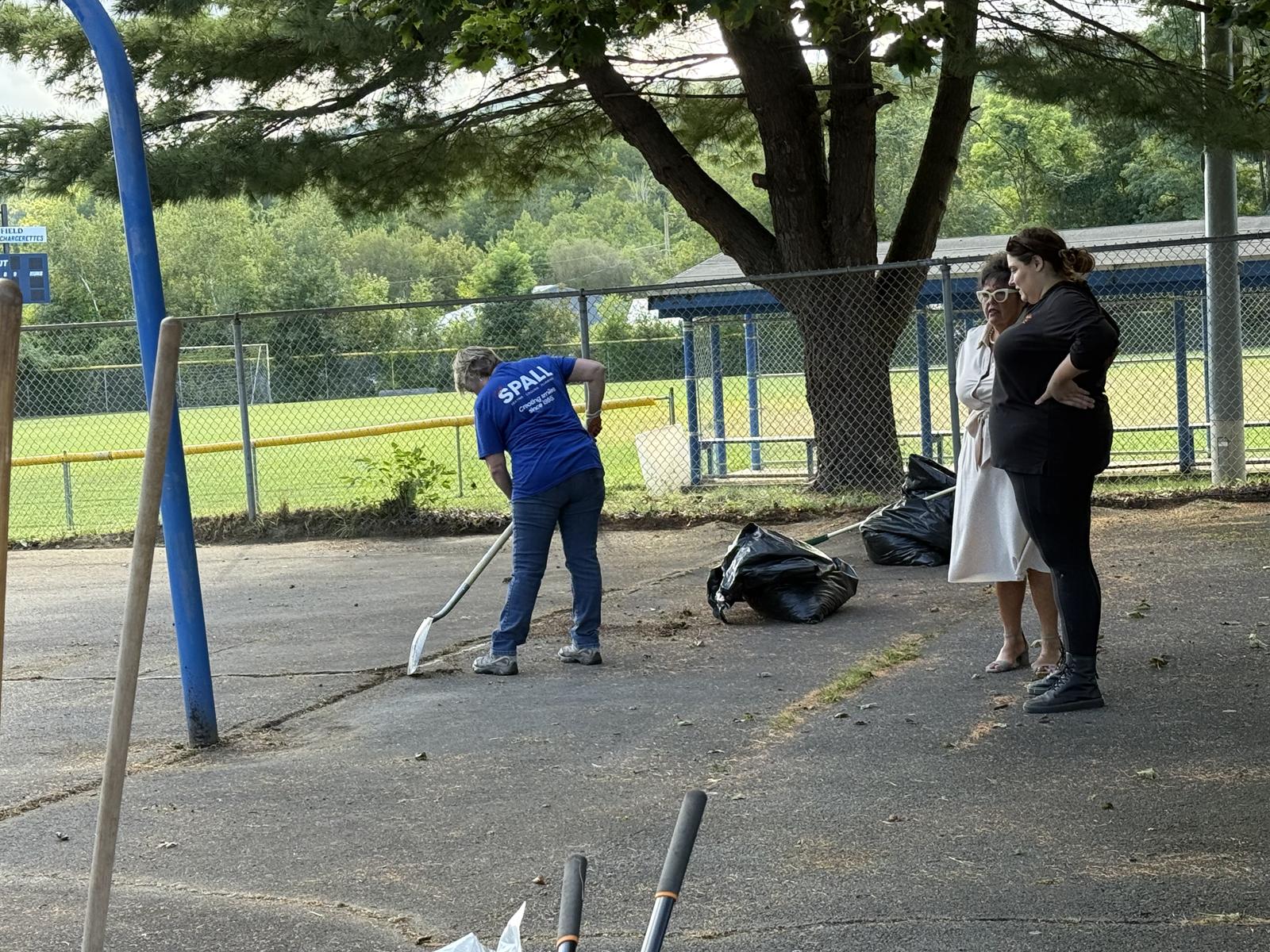 A T.E. Spall & Son volunteer shoveling debris into bags at Cerra Park.